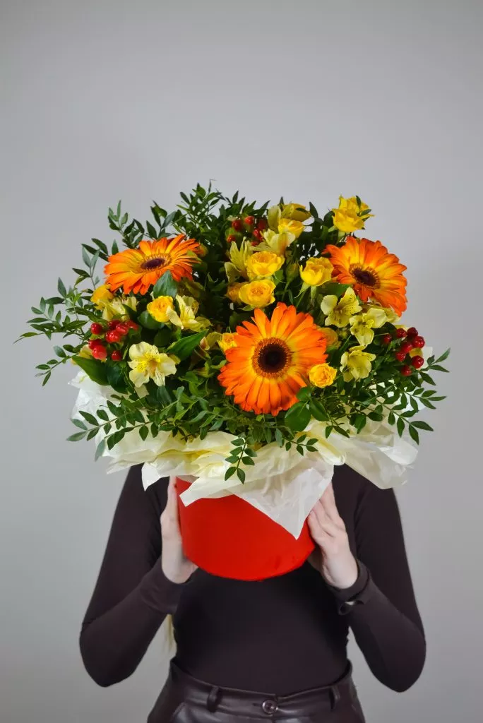 Композиция в шляпной коробке из гербер, гиперикума, альстромерии, кустовой розы и фисташки