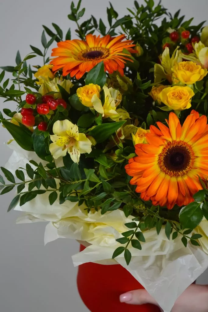 Композиция в шляпной коробке из гербер, гиперикума, альстромерии, кустовой розы и фисташки