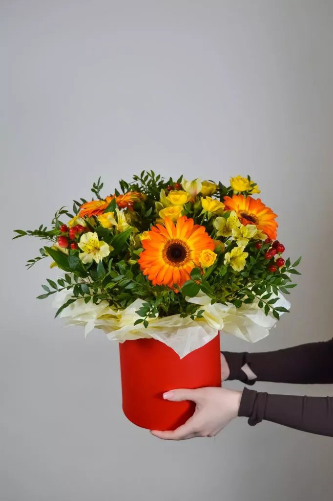 Композиция в шляпной коробке из гербер, гиперикума, альстромерии, кустовой розы и фисташки